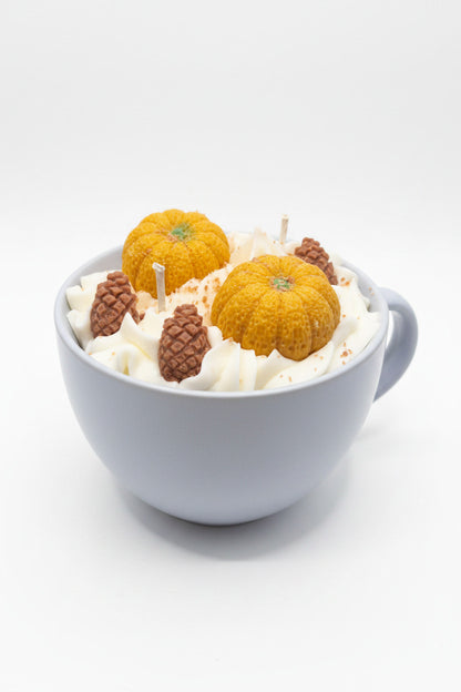 Herbstbecher Kürbis  – hellblauer Keramikbecher mit weißem Wachs, orangen Kürbis- und braunen Tannenzapfen-Kerzen, Frontansicht
