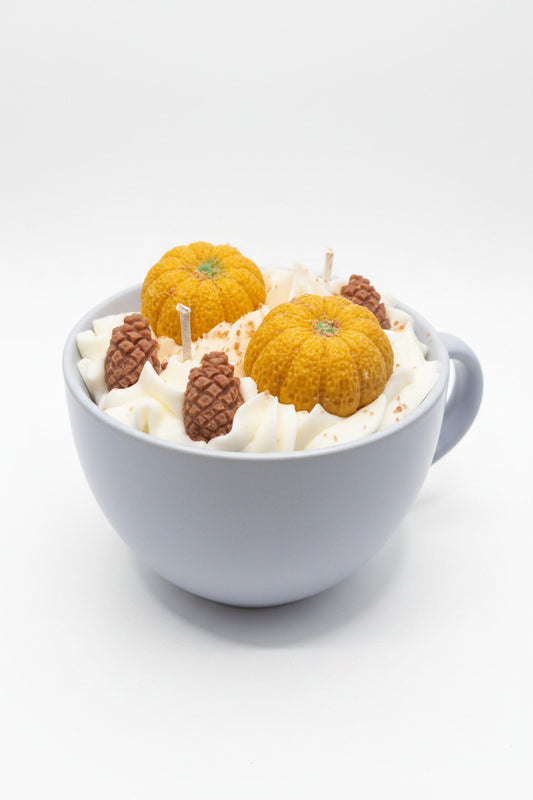 Herbstbecher Kürbis  – hellblauer Keramikbecher mit weißem Wachs, orangen Kürbis- und braunen Tannenzapfen-Kerzen, Frontansicht